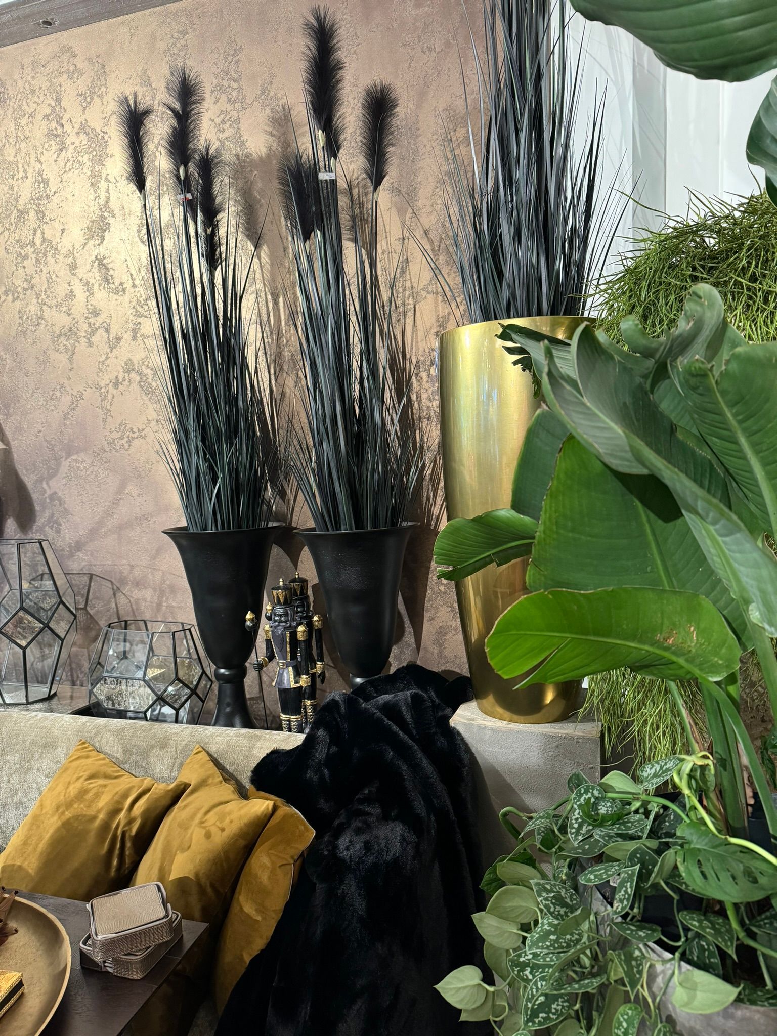 Ein Wohnzimmer mit Sofa, Kissen, Vasen und Pflanzen.