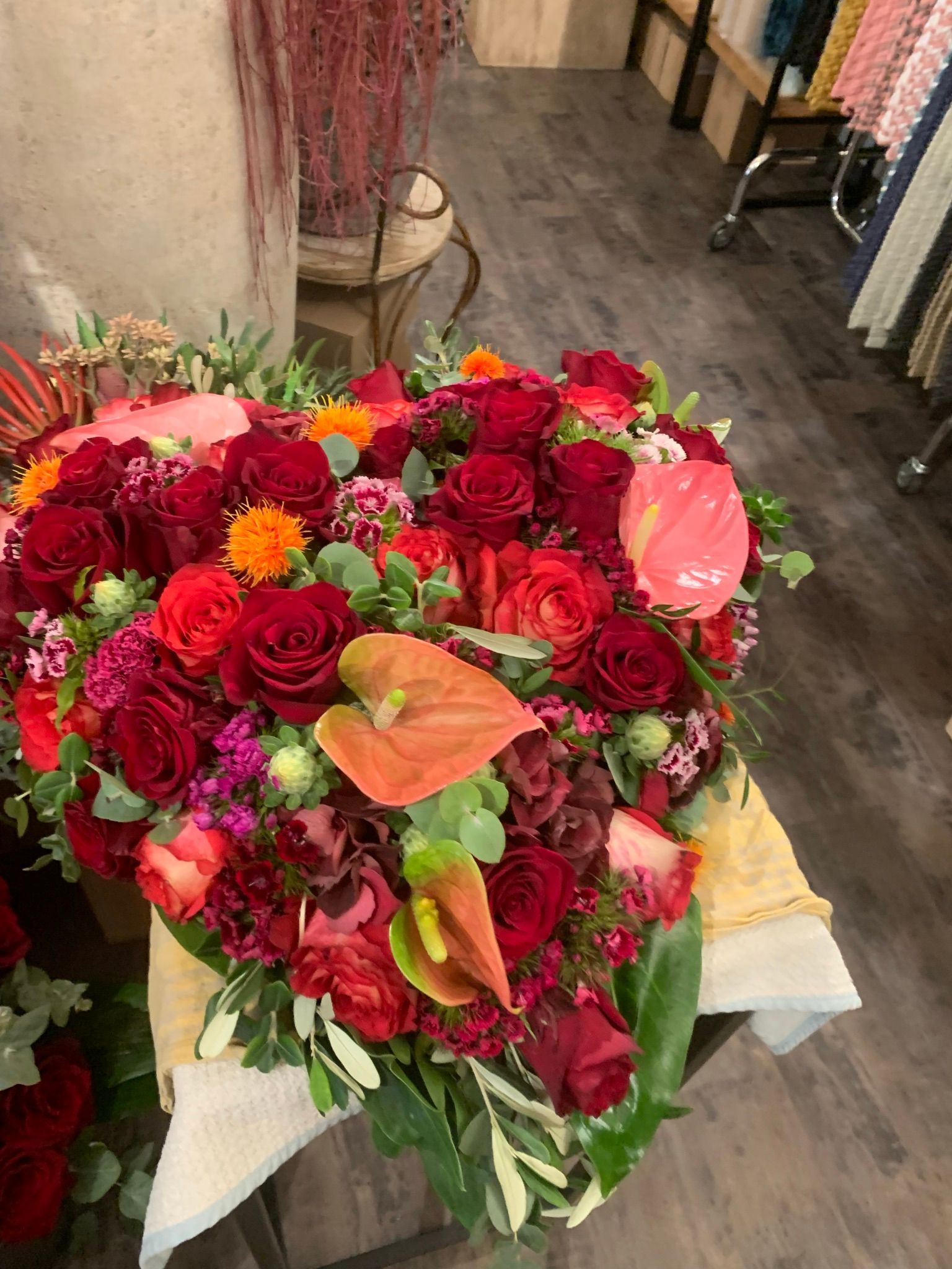 Auf einem Tisch steht ein herzförmiger Strauß roter Rosen und anderer Blumen.