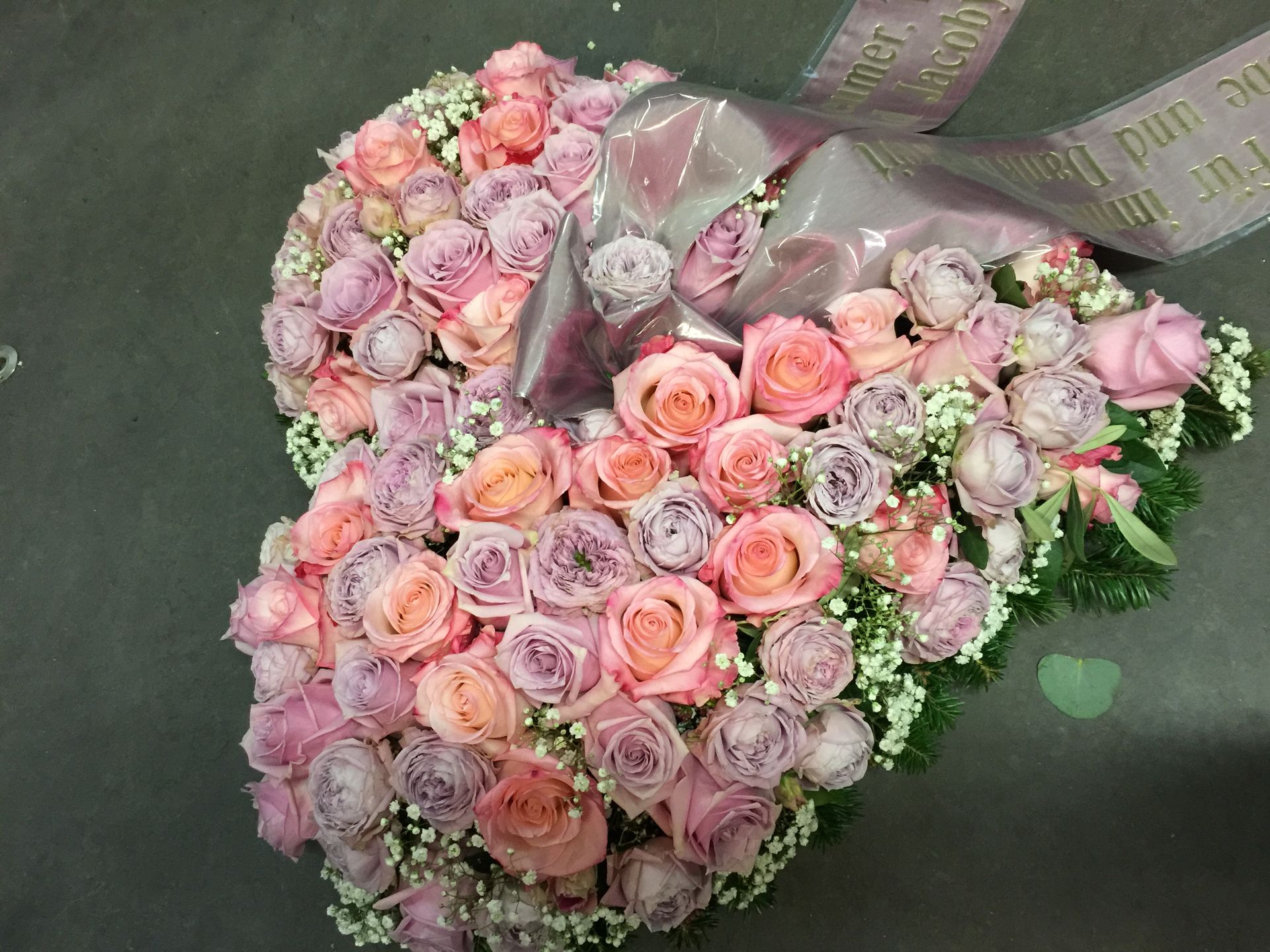 Ein herzförmiger Kranz aus rosa Rosen und Schleierkraut