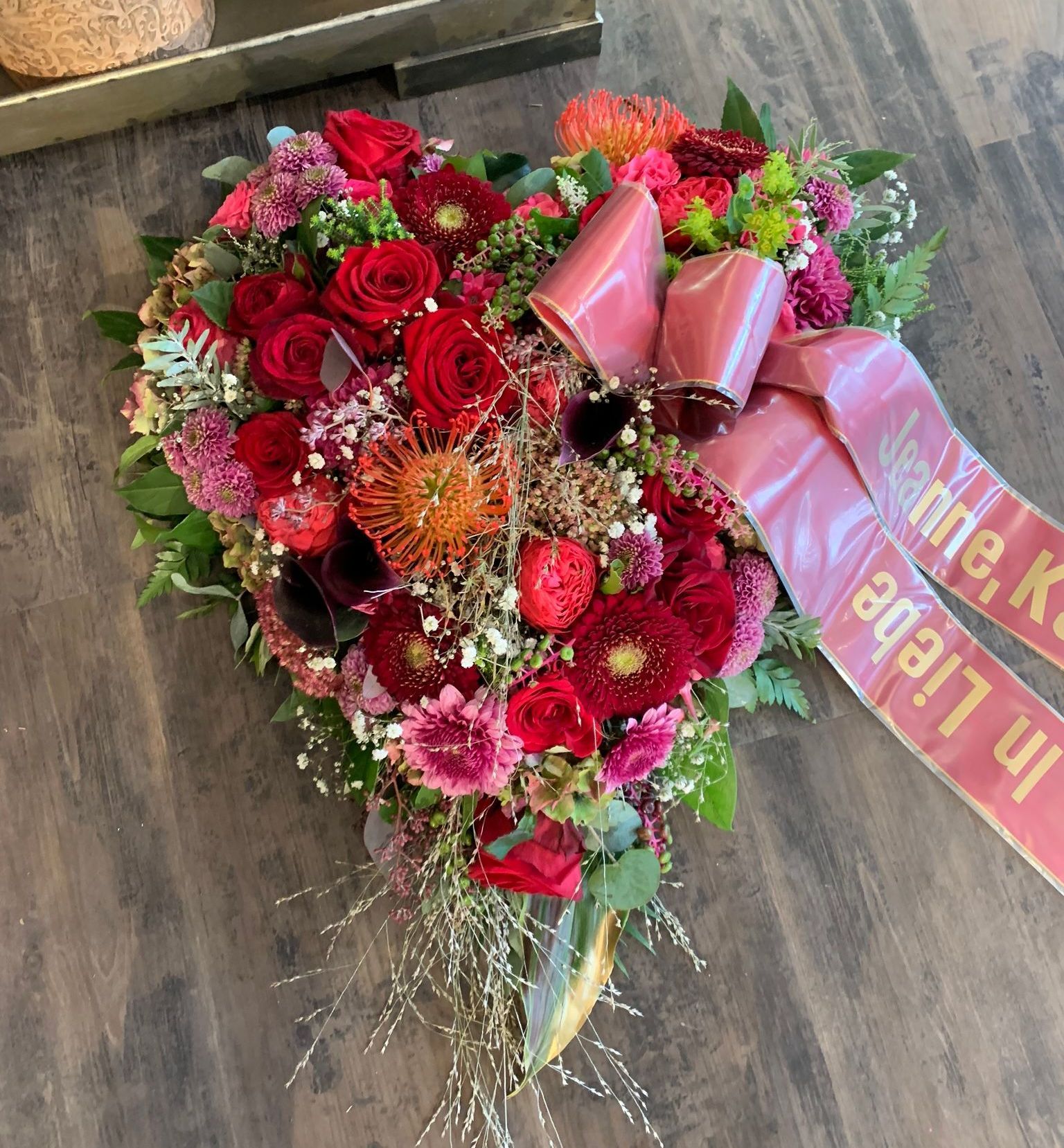 Ein herzförmiger Blumenstrauß mit einer Schleife mit der Aufschrift „in Liebe“