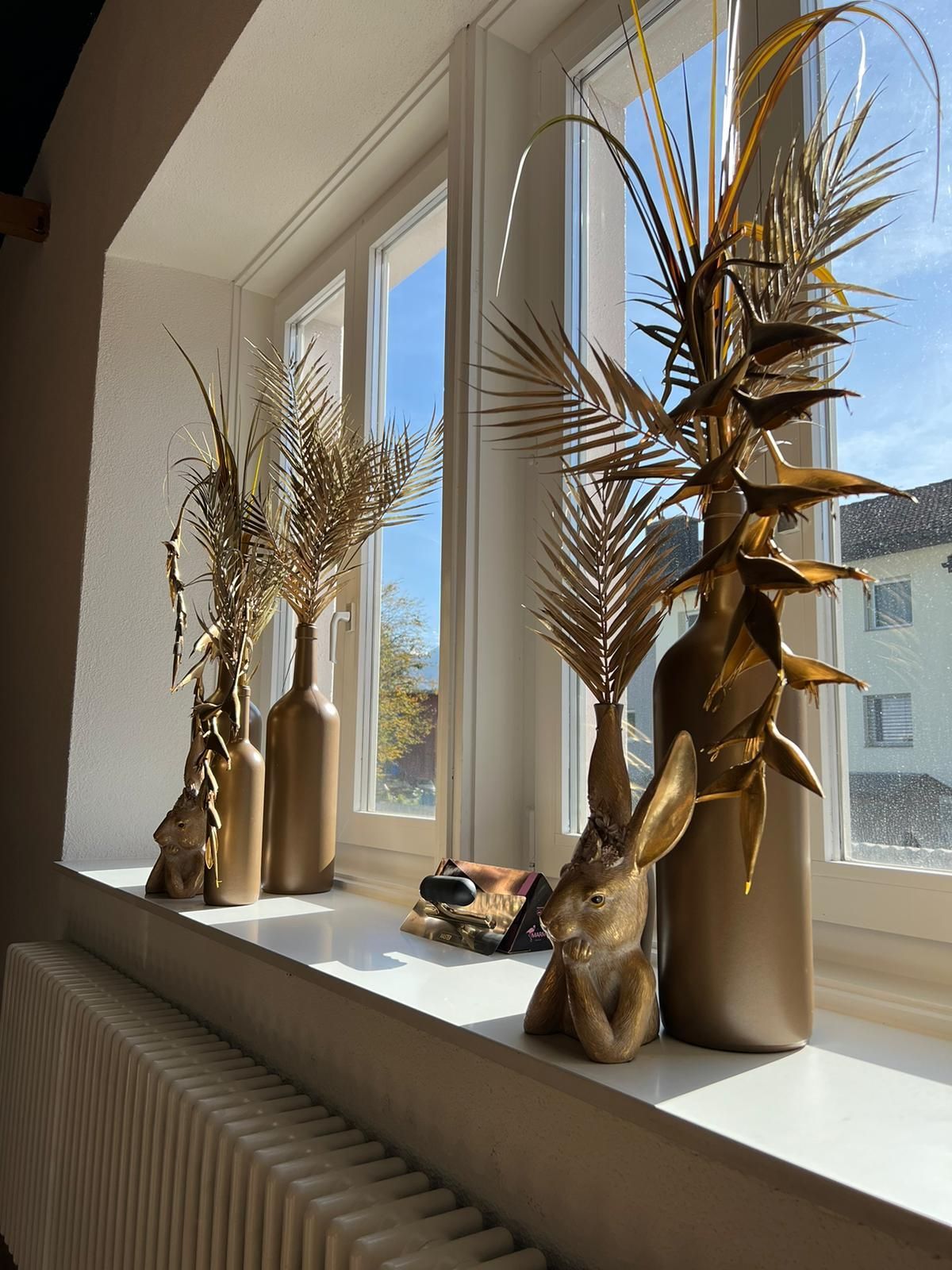 Eine Reihe von Vasen steht auf einem Fensterbrett neben einem Heizkörper.