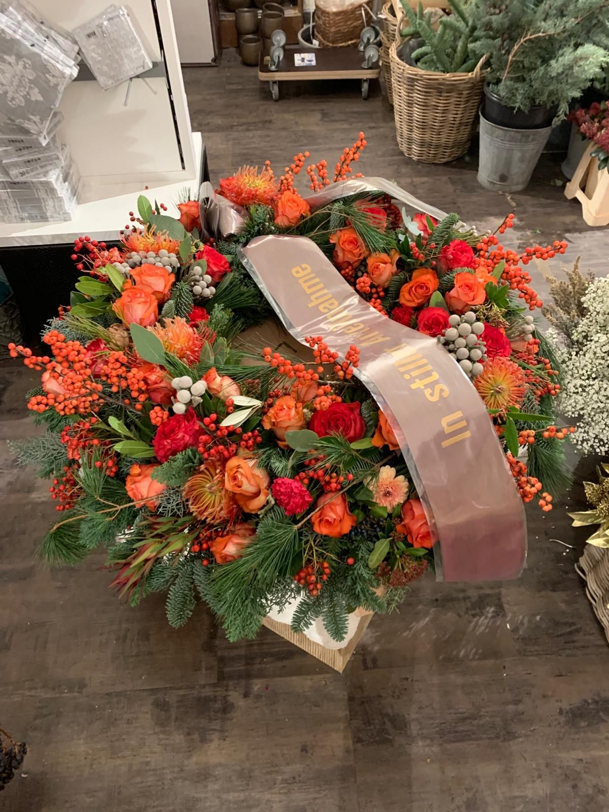 Auf einem Holztisch liegt ein Kranz mit einer Schleife.