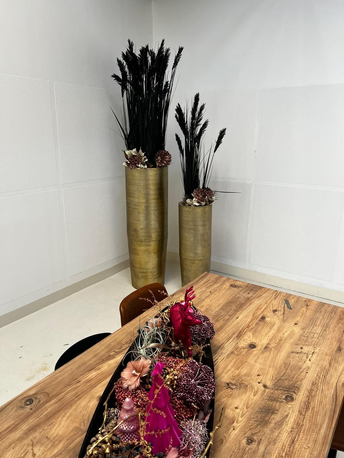 Ein Holztisch mit zwei Vasen voller Blumen darauf.