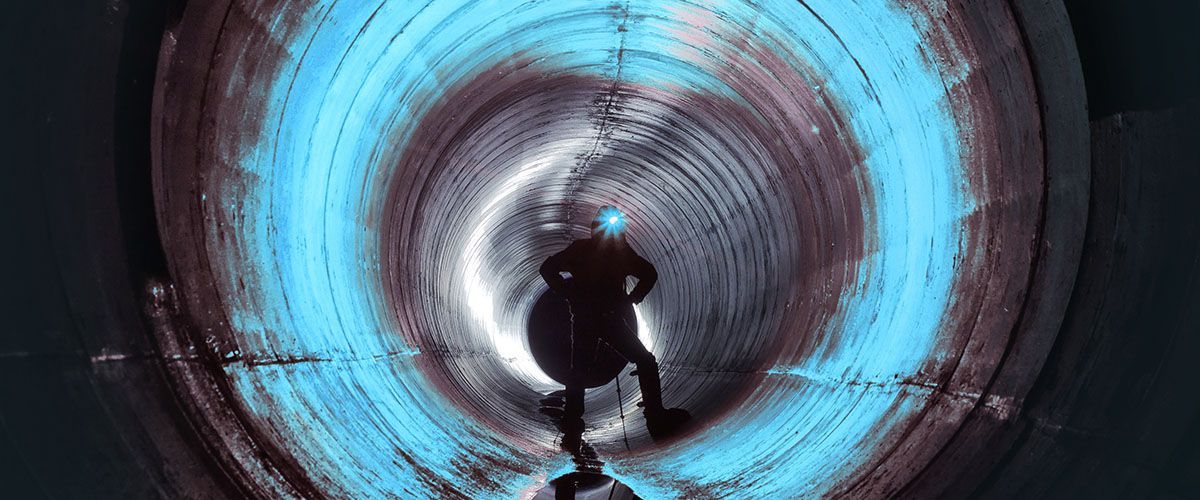 Eine Person steht mit einer Lampe auf dem Kopf in einem Tunnel.