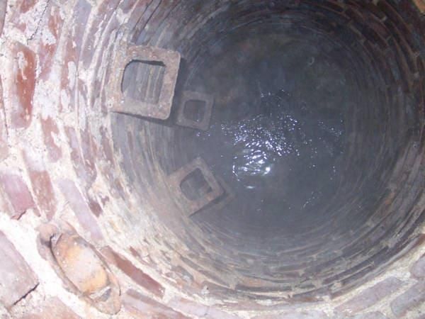 Ein Kanaldeckel mit einem Loch in der Mitte, das mit Wasser gefüllt ist.
