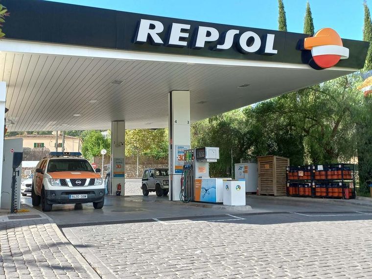 Un camión Nissan está estacionado frente a una gasolinera Repsol.