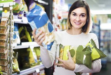 Una mujer sostiene una bolsa de patatas fritas en un supermercado.
