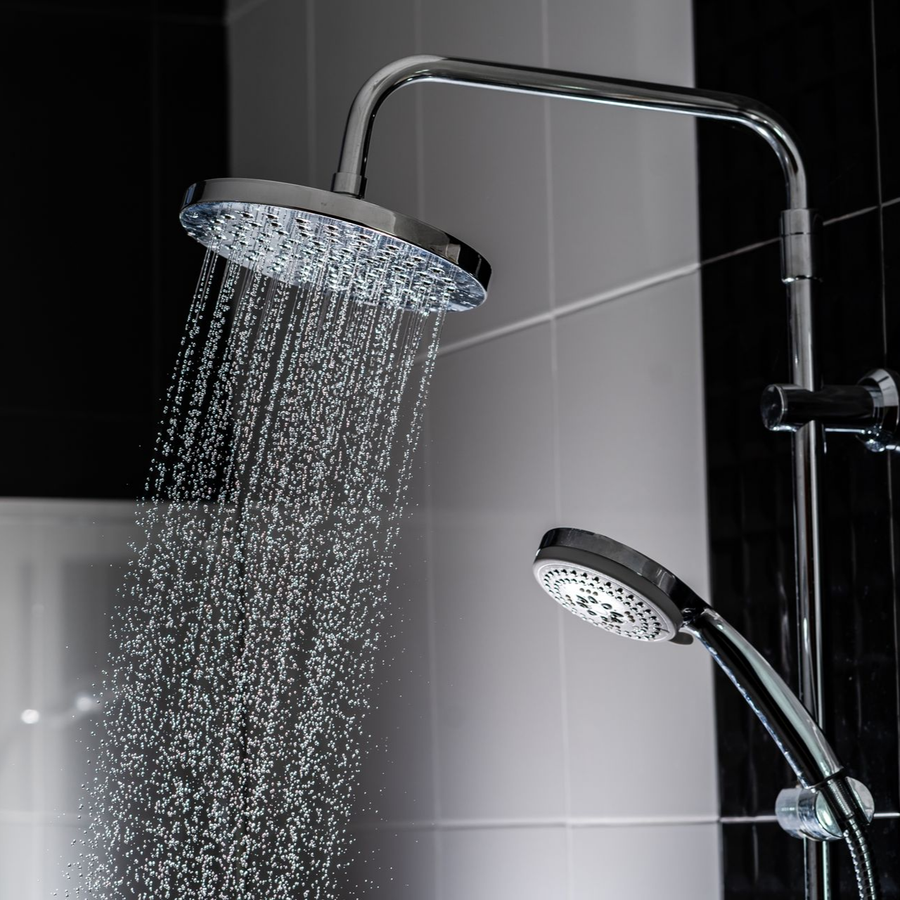 Pommeau de douche avec jet d'eau, à côté d'une pomme de douche à main.