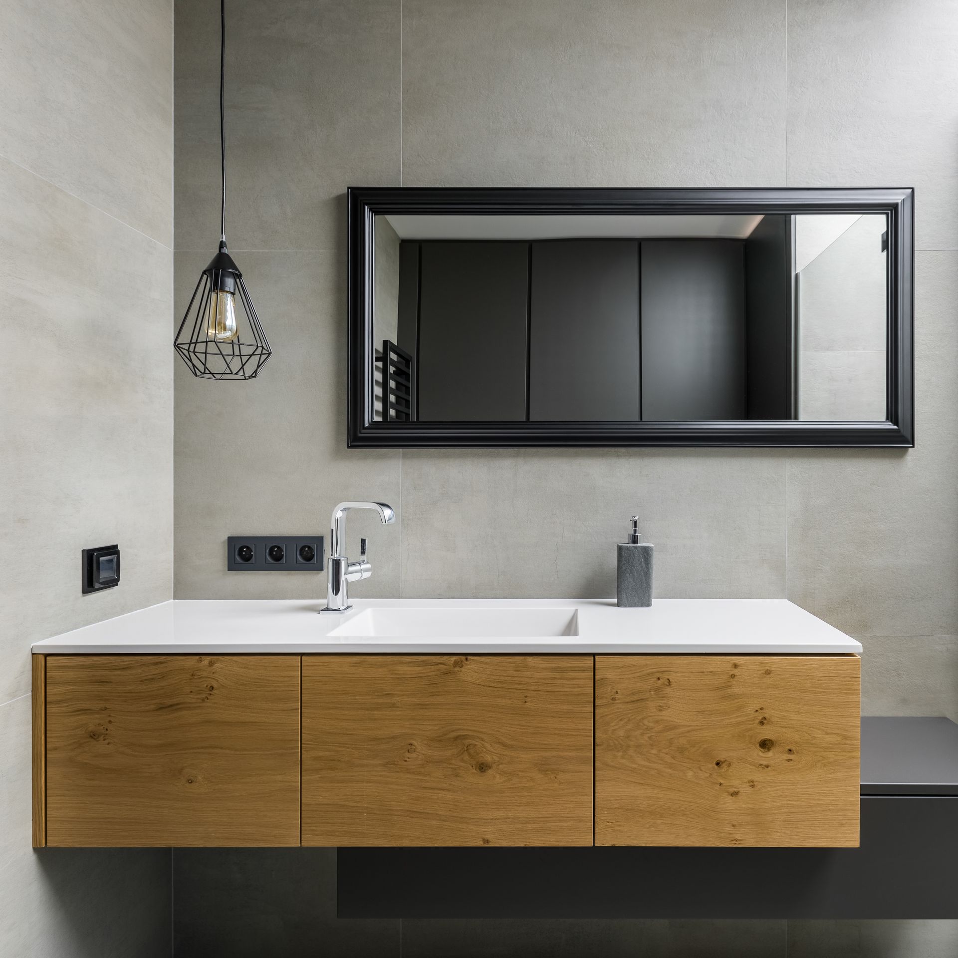 Salle de bains moderne avec vanité en bois, grand miroir et luminaire suspendu.