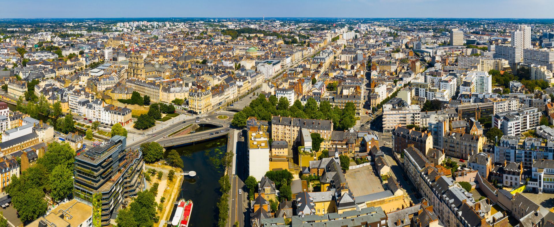 Vue aérienne d'une ville avec des bâtiments, une rivière, des ponts et un ciel bleu.