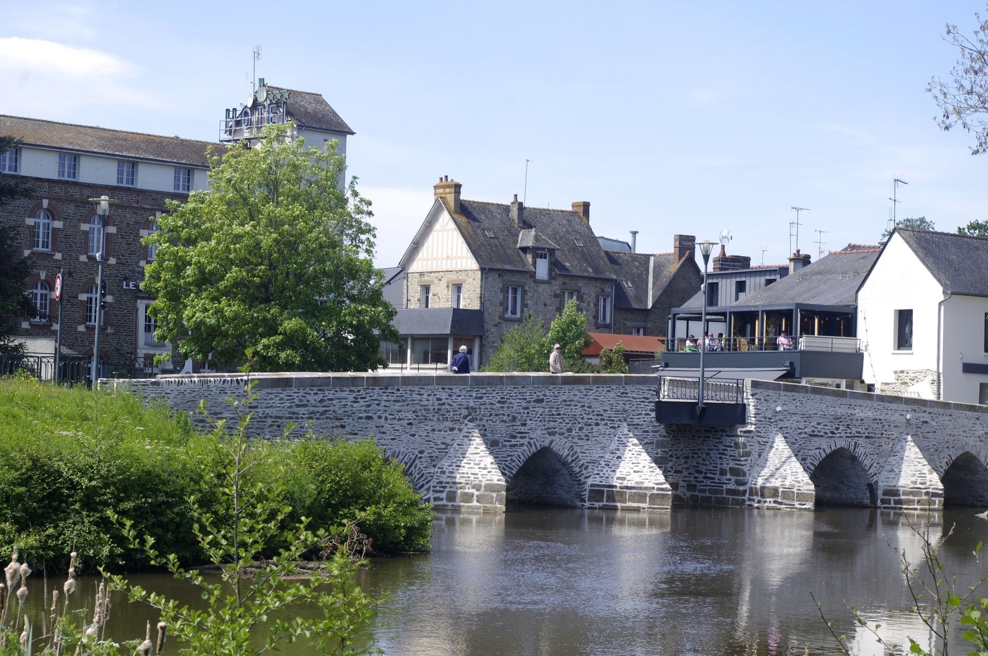 Pont de pierre sur l'eau, bâtiments en arrière-plan. Journée ensoleillée.
