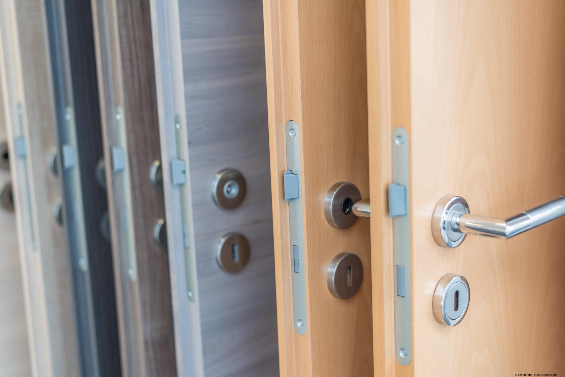 Detailaufnahme mehrerer Holztüren mit Metallgriffen und Schließsystemen.