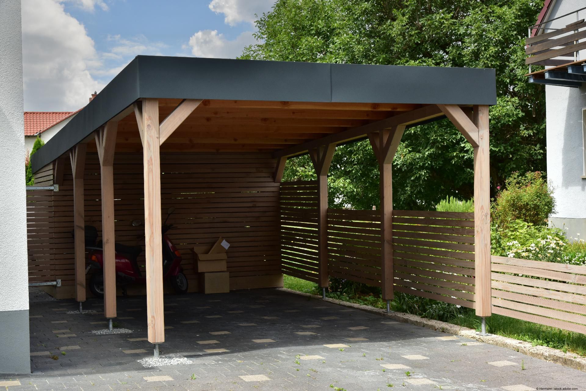 Langer Gartenzaun aus rotbraunem Holz mit dekorativer Abdeckung.