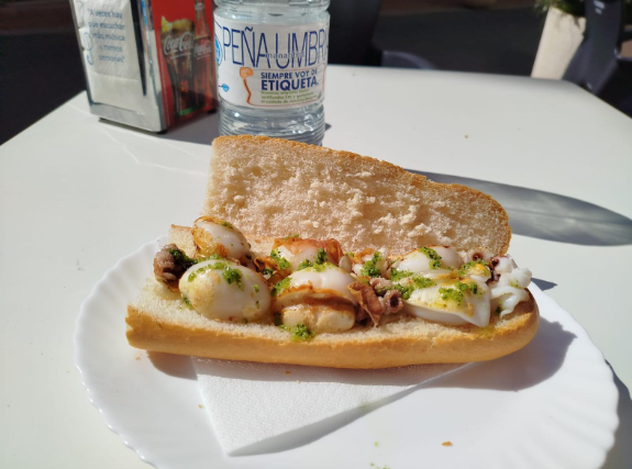 Un sándwich en un plato junto a una botella de agua Peña Liner