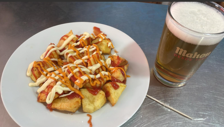 Un plato de comida y un vaso de cerveza en una mesa.