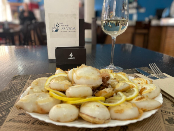 Un plato de comida y una copa de vino en una mesa