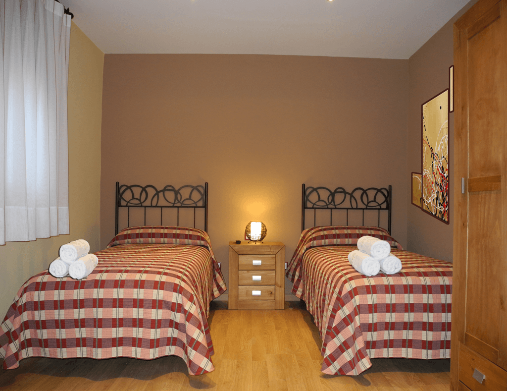 Un dormitorio con dos camas y una mesita de noche.