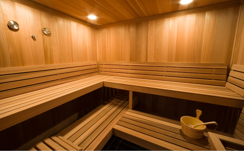 Una sauna de madera con un cubo de agua en el suelo.