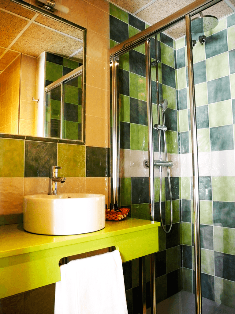 Un baño con azulejos verdes y un lavabo.