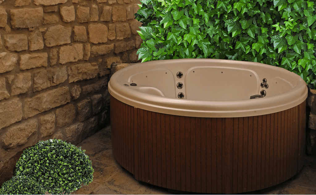 Una bañera de hidromasaje redonda está situada delante de una pared de piedra.