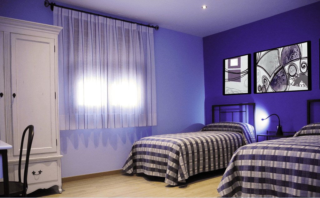 Un dormitorio con dos camas y paredes moradas.