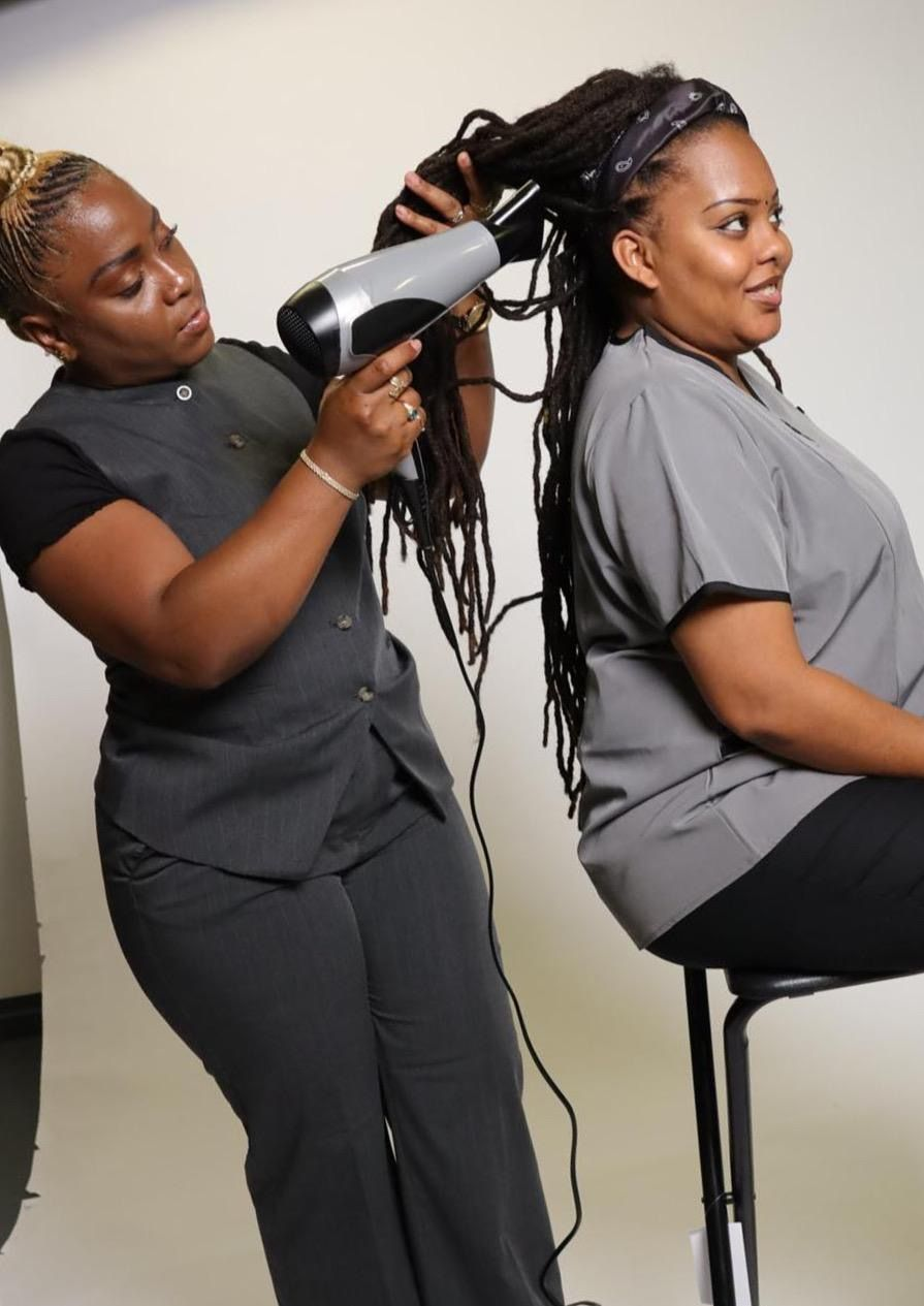 Femme à la peau foncée, souriante et touchant ses joues, sur fond marron.