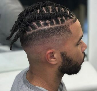 Homme aux cheveux foncés et texturés, coiffés en dégradé, et portant une barbe courte, dans un salon de coiffure.