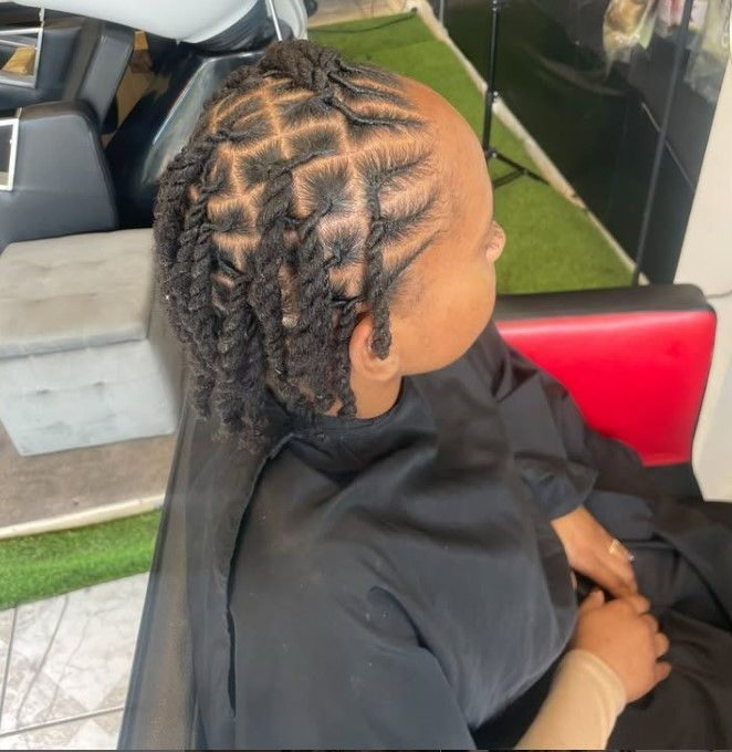 Femme aux tresses torsadées et à motifs ; cheveux noirs, dans un salon de coiffure.