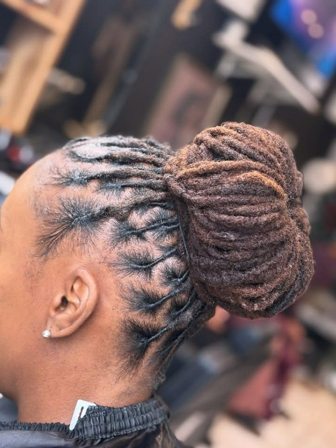 Femme aux dreadlocks brunes relevées en chignon.
