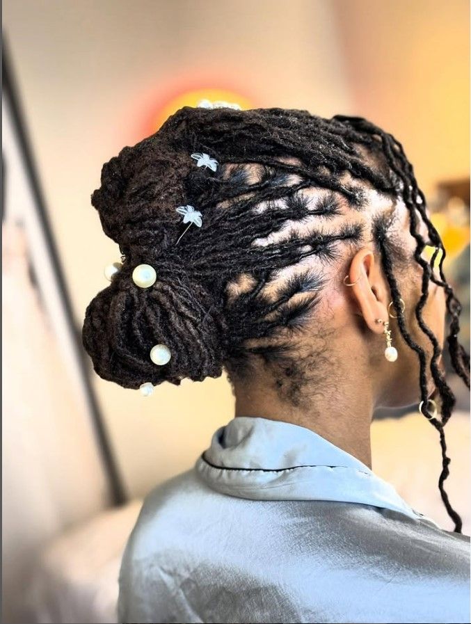 Personne aux cheveux noirs tressés en chignon orné d'accessoires blancs.