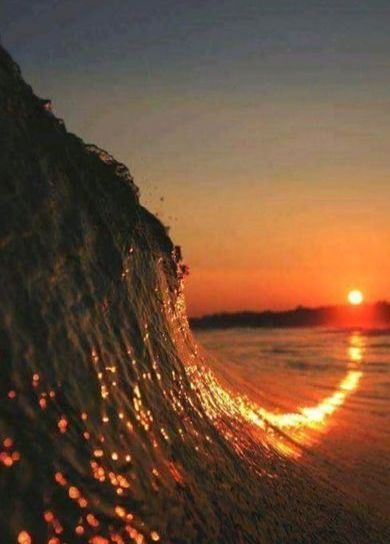 Una ola rompe en la playa al atardecer