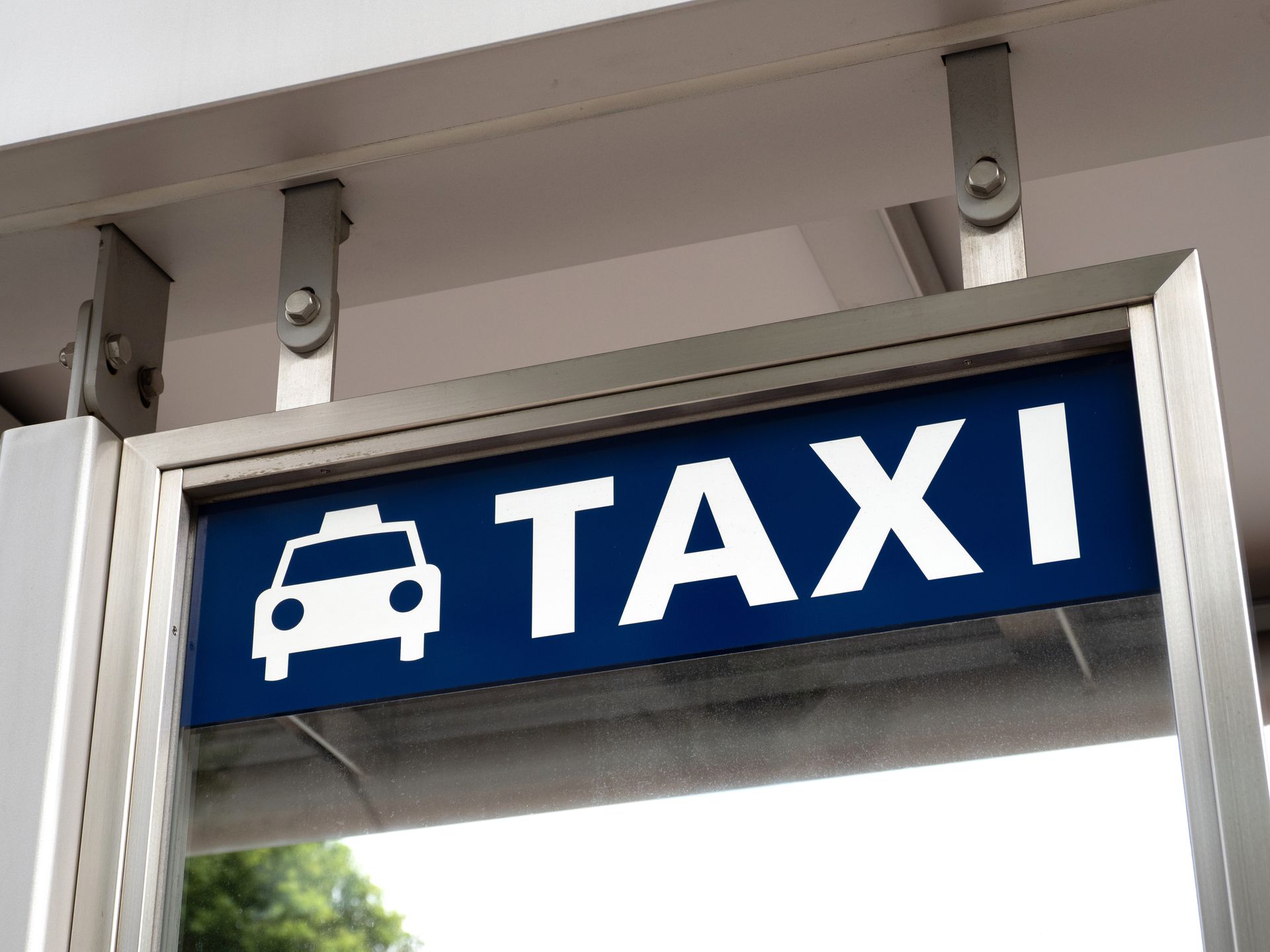 Panneau de taxi avec icône de voiture sur fond bleu.