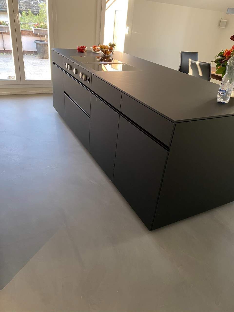 Schwarze Küchenzeile mit grauem Boden aus Betonspachtel