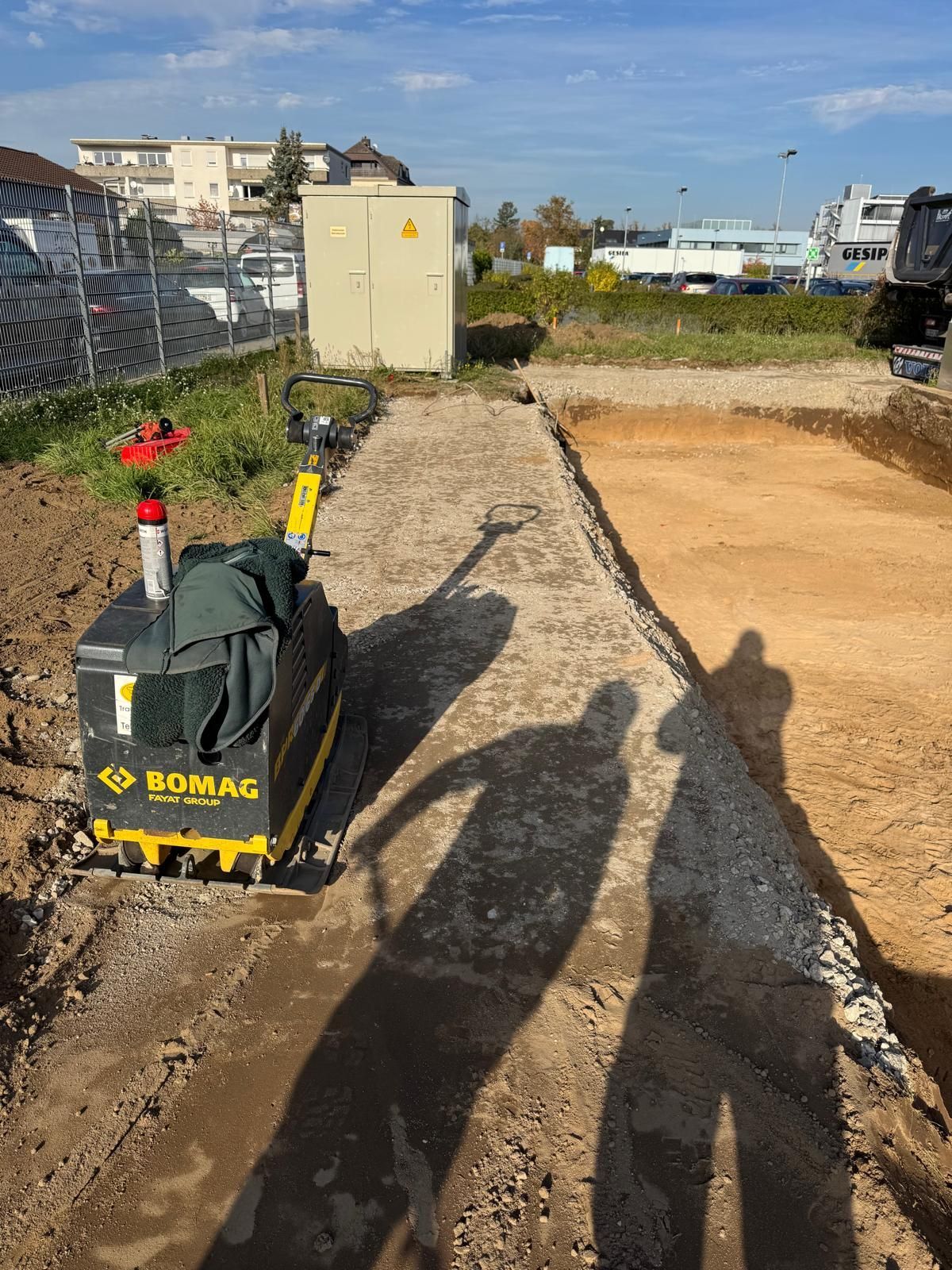 Baustelle mit einer BOMAG-Verdichtungsmaschine zur Vorbereitung eines Schotterwegs.