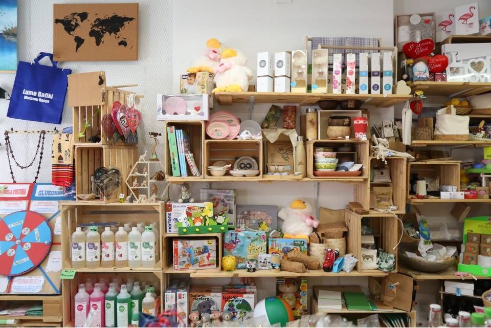 All'interno di un negozio, scaffali pieni di vari articoli in vendita, tra cui giocattoli, candele e decorazioni.