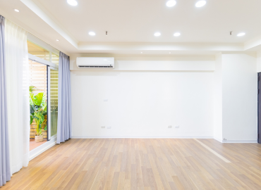 Une grande pièce vide avec un plancher en bois et des murs blancs.