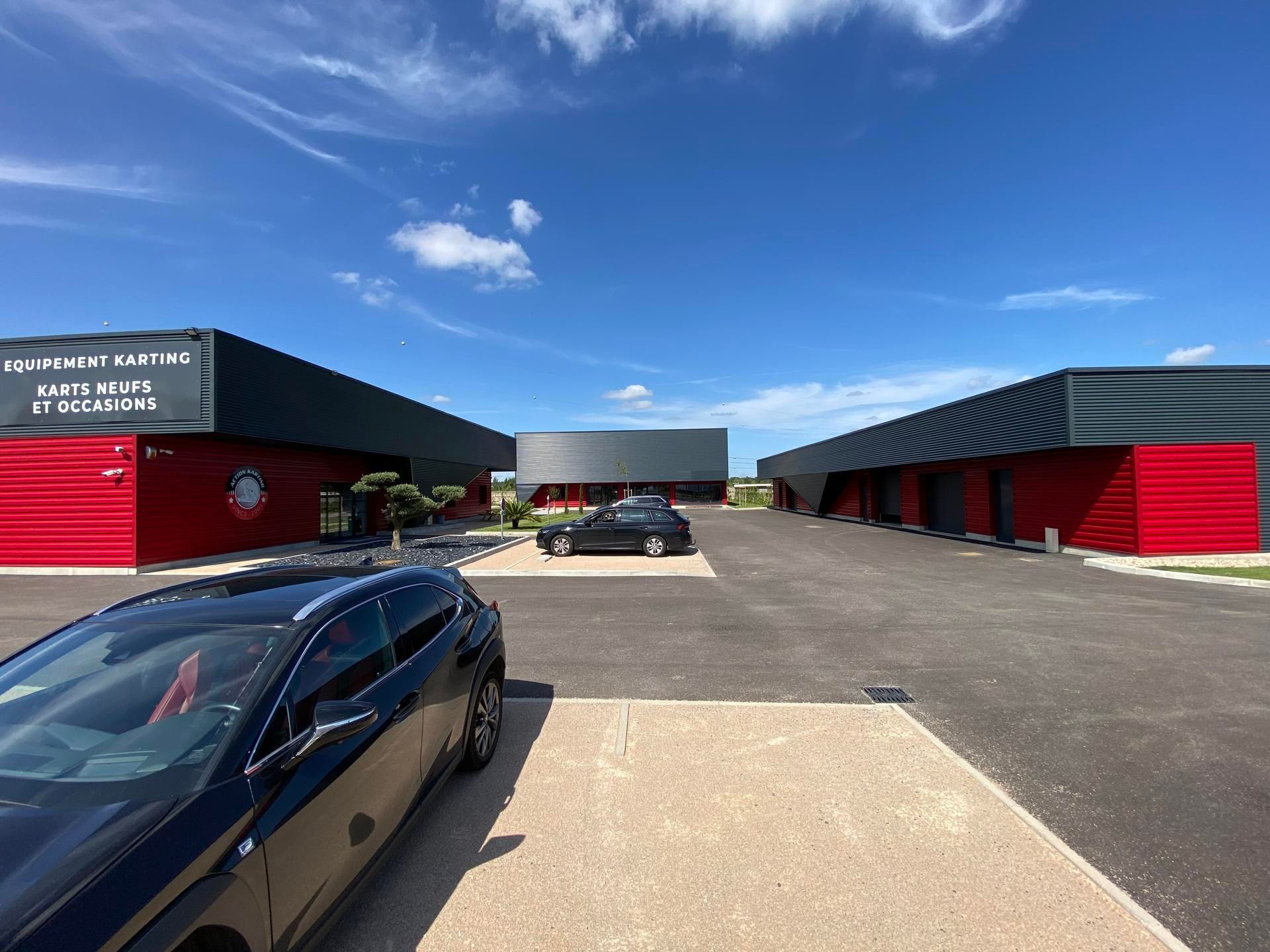 Vue extérieure d'un complexe commercial moderne avec des bâtiments noir et rouge sous un ciel bleu.
