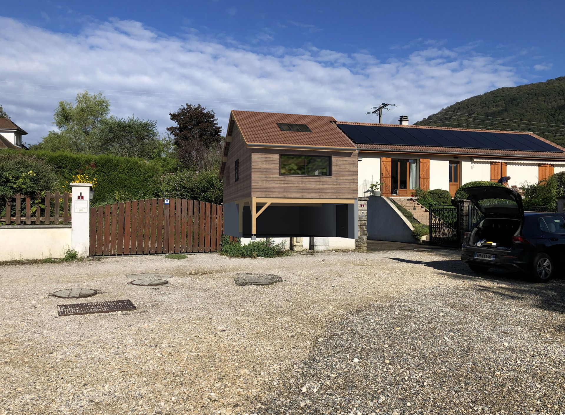 Une extension de bâtiment en bois sur un petit parking. Bâtiment marron, parking en gravier, ciel bleu.