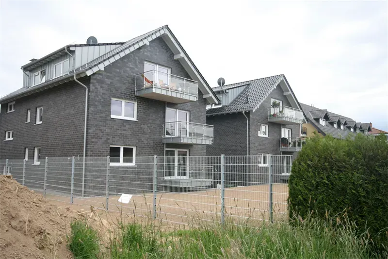 Ein Zaun umgibt eine Reihe von Wohnhäusern