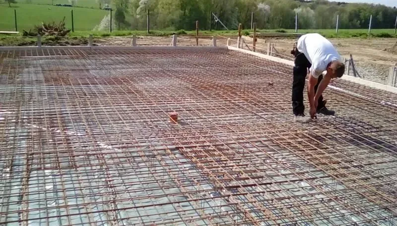 Ein Mann beugt sich über einen Betonboden.