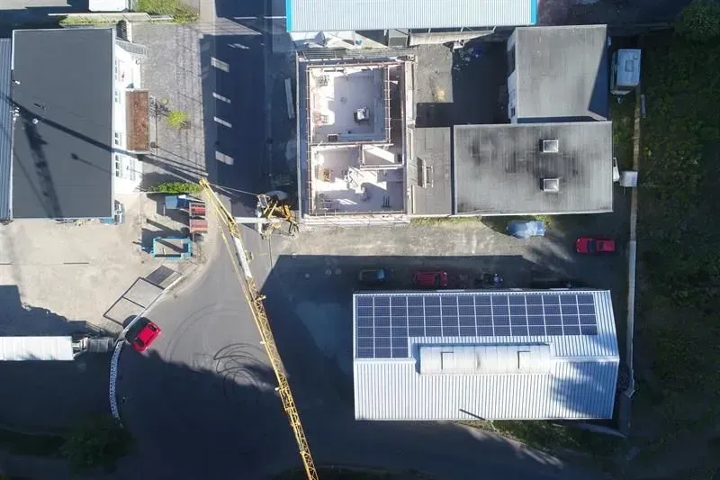 Eine Luftaufnahme eines im Bau befindlichen Gebäudes mit Solarmodulen auf dem Dach.