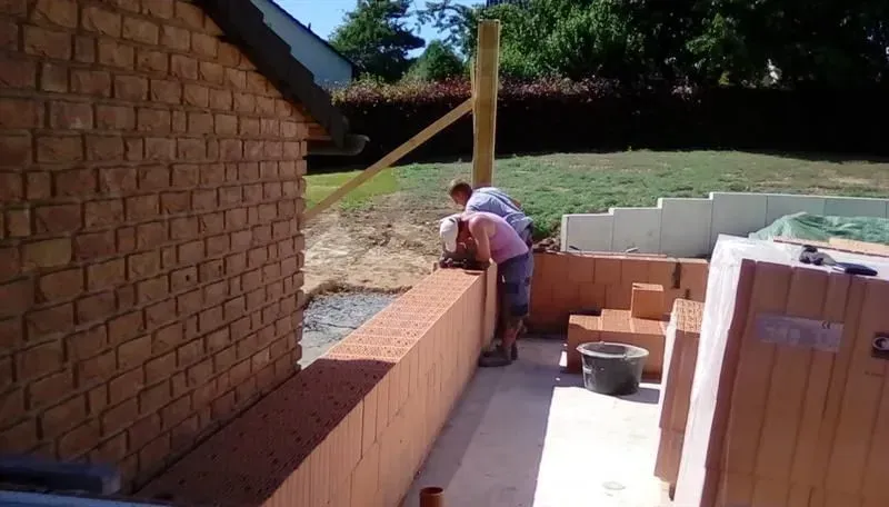 Eine Gruppe von Leuten arbeitet an einer Ziegelmauer.