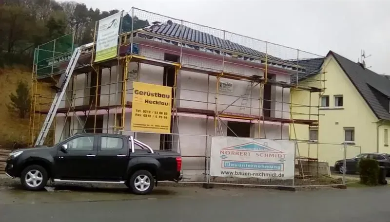 Ein schwarzer Lastwagen parkt vor einem im Bau befindlichen Gebäude.