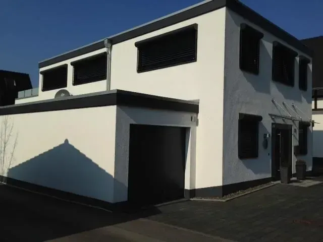 Ein weißes Haus mit schwarzen Verzierungen hat ein schwarzes Garagentor