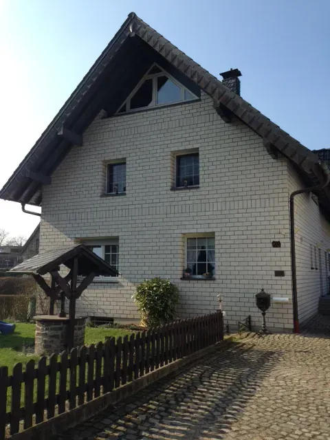 Ein weißes Backsteinhaus mit einem Holzzaun davor