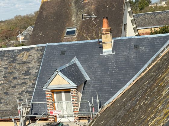 Toiture en ardoise, cheminée en briques et petite lucarne sur une maison.