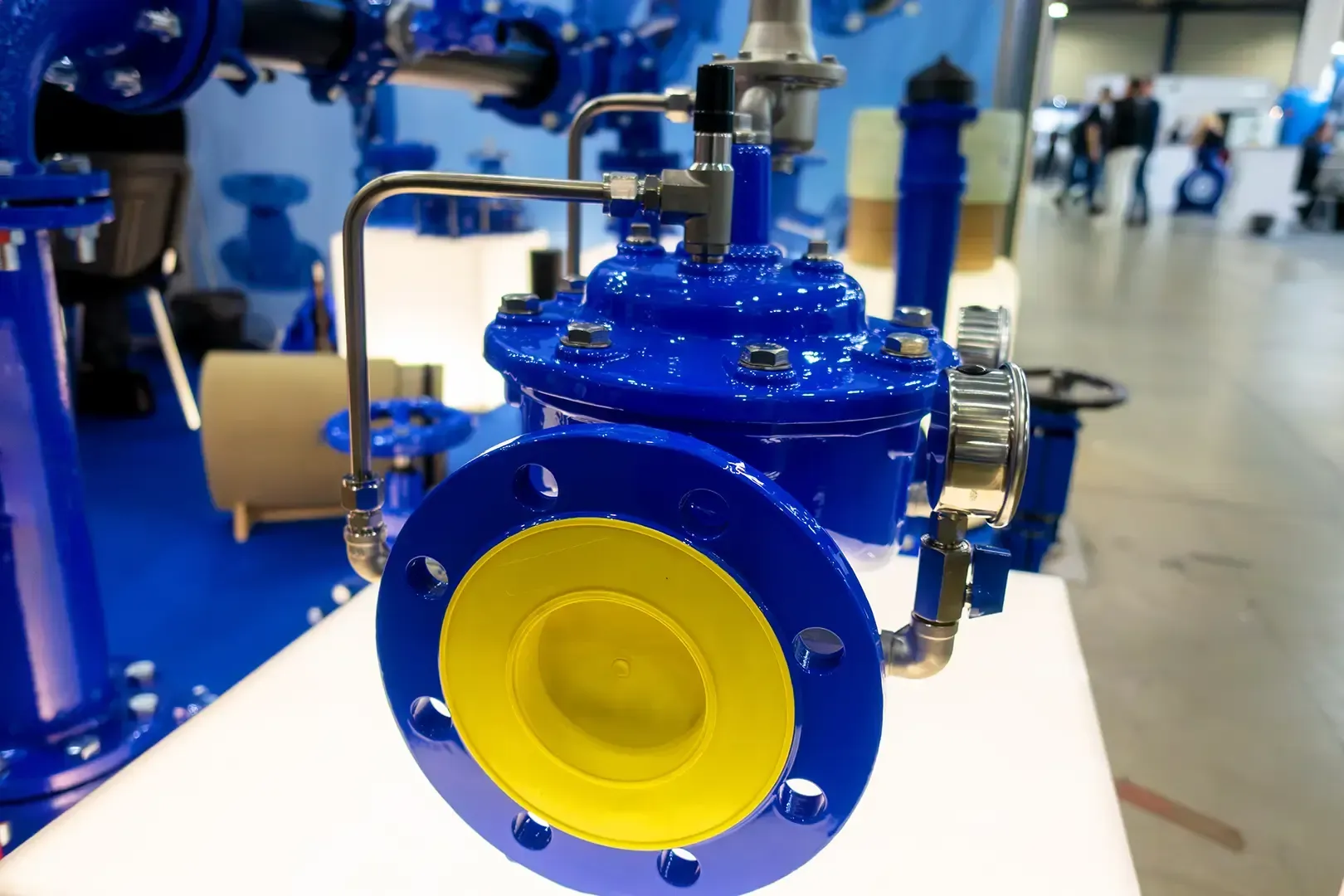 Blaues Industrieventil mit gelbem Innenring, Rohren und Armaturen.
