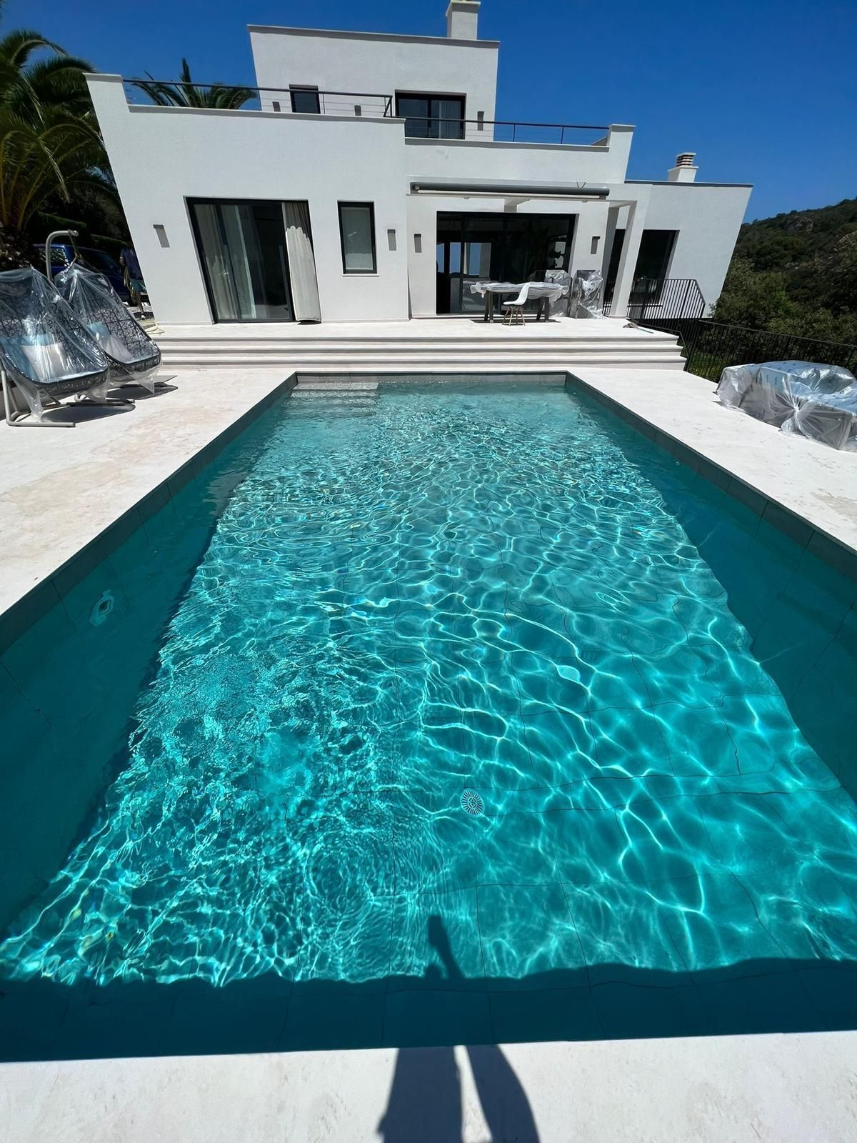 Villa moderna blanca con piscina turquesa bañada por la luz del sol.