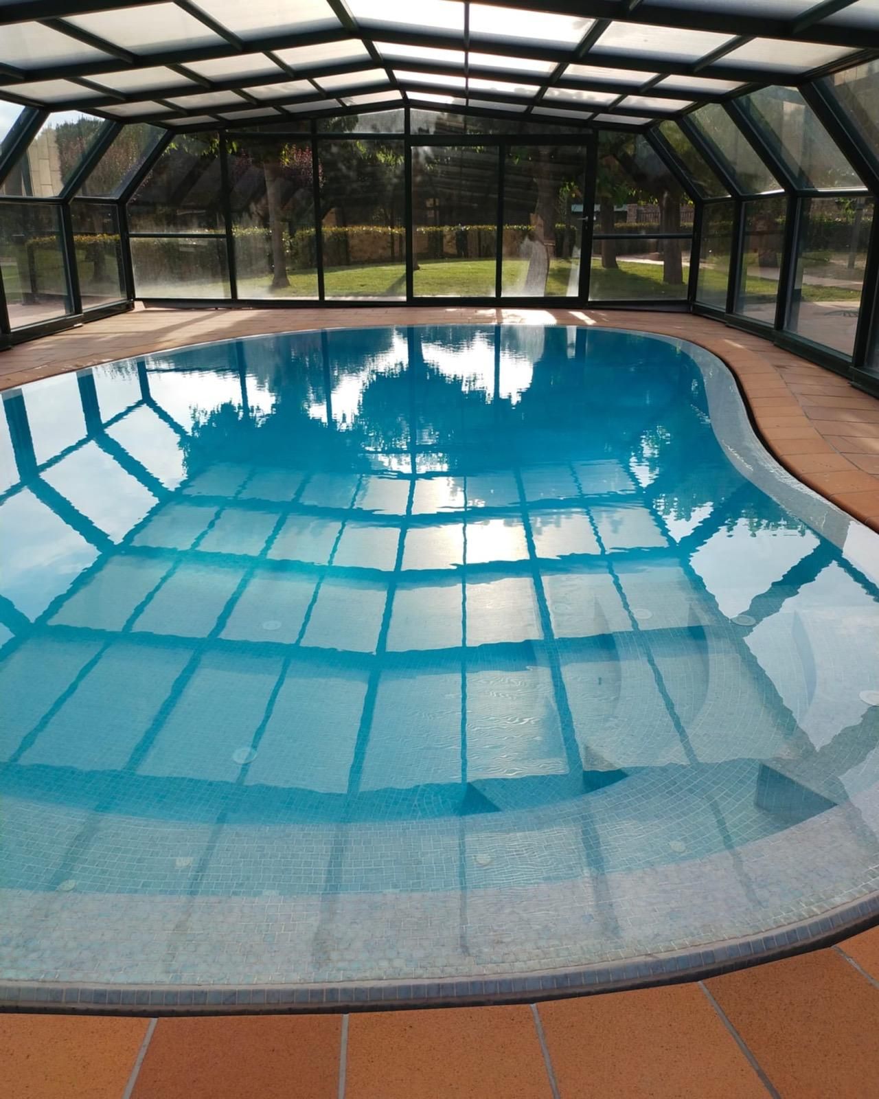Piscina cubierta con mosquitera, agua azul y terraza curva.