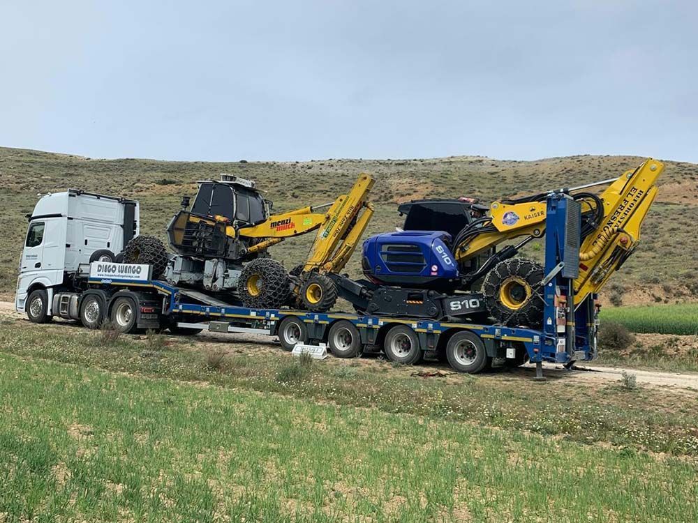 Un camión transporta un tractor en un remolque en un campo.
